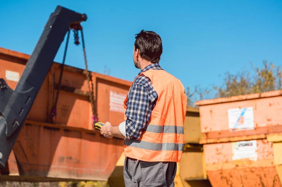 a worker wearing a bright orange vest at a construction site is overseeing equipment