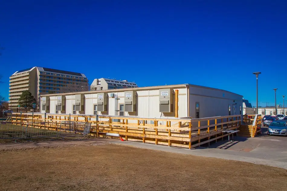 The Exterior of an S-Plex modular building with air conditioning in front of a cityscape or office buildings.