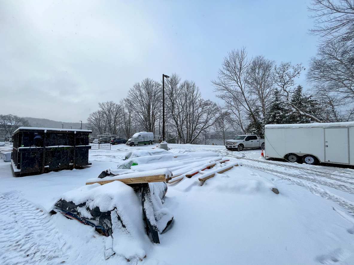 A snowy construction site with materials and equipment covered in snow.